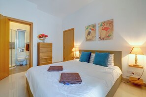 Ett hotellrum med en säng, två sänglampor, en byrå i trä, en toalett och en dusch.