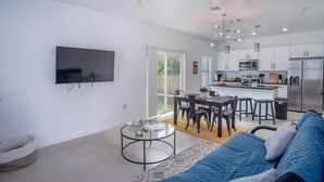 Een moderne woonkamer met een televisie, een ronde salontafel en een blauwe bank.