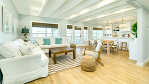 Un salon spacieux avec un canapé blanc, une table basse en bois et un coin repas comprenant une table et des chaises en bois.