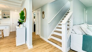 Un intérieur moderne comprenant un escalier, un coin cuisine et un salon avec un canapé.