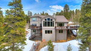 Una casa de dos pisos con un balcón, una escalera y un patio cubierto de nieve.