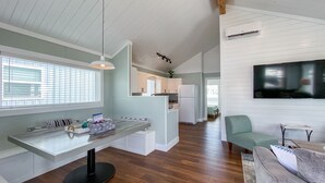 Una cocina moderna con una isla central, suelo de madera y un comedor con mesa y sillas.