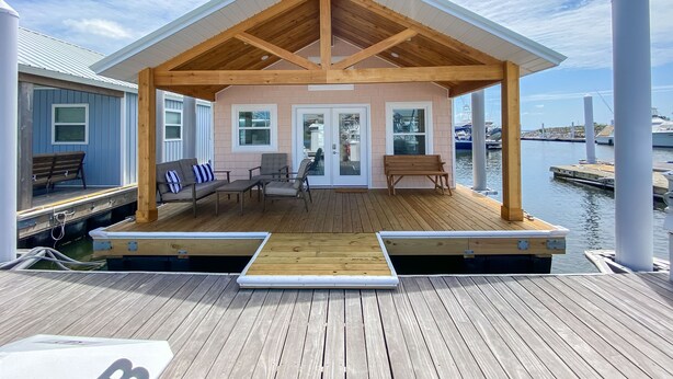 Una terraza techada al aire libre con piso de madera, un banco y una mesa.
