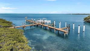 A pier extending into clear blue water with a boat docked at the end.