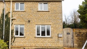 A stone house with two windows and a chimney.