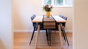 A dining area with a wooden table, black chairs, a woven placemat, and a vase of flowers.