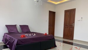A neatly arranged bedroom with a bed, purple bedding, and a red bow on the bed. - Magnificent house in quiet residential area (Yaoundé)