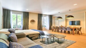 Une chambre d’hôtel moderne dotée d’un grand lit, d’un canapé, d’une table à manger avec des chaises et d’un téléviseur fixé au mur.
