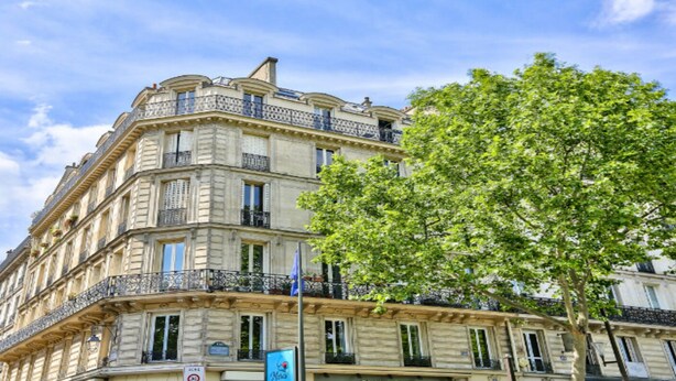 Un immeuble à plusieurs étages de style architectural classique, doté de balcons et de grandes fenêtres.
