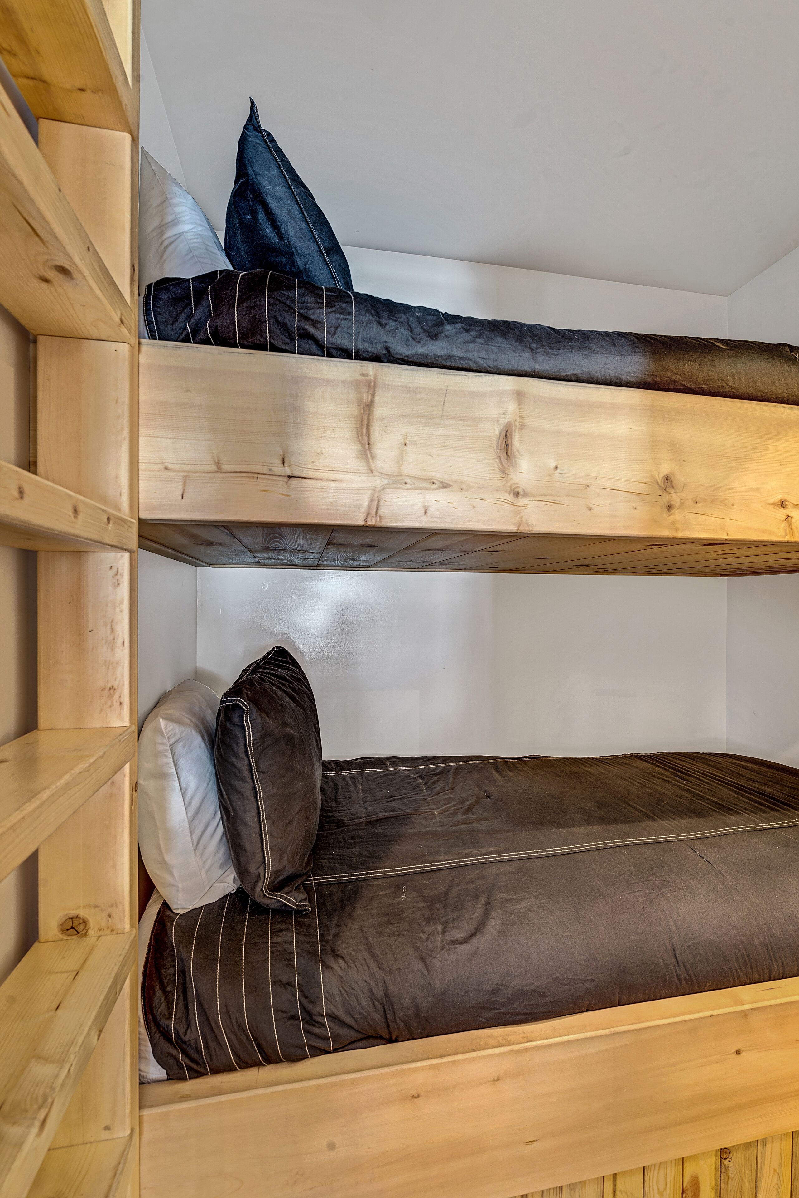 Un lit superposé à deux niveaux, chaque niveau étant équipé d’oreillers et d’une couverture.