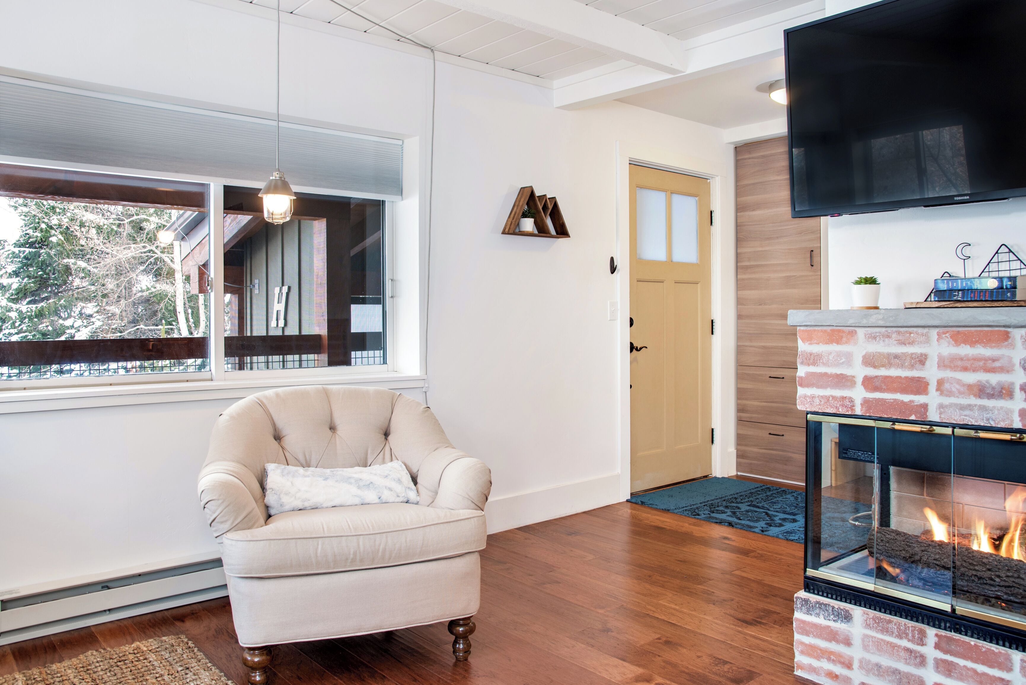 A living room with a fireplace, a sofa, and a TV mounted on the wall.