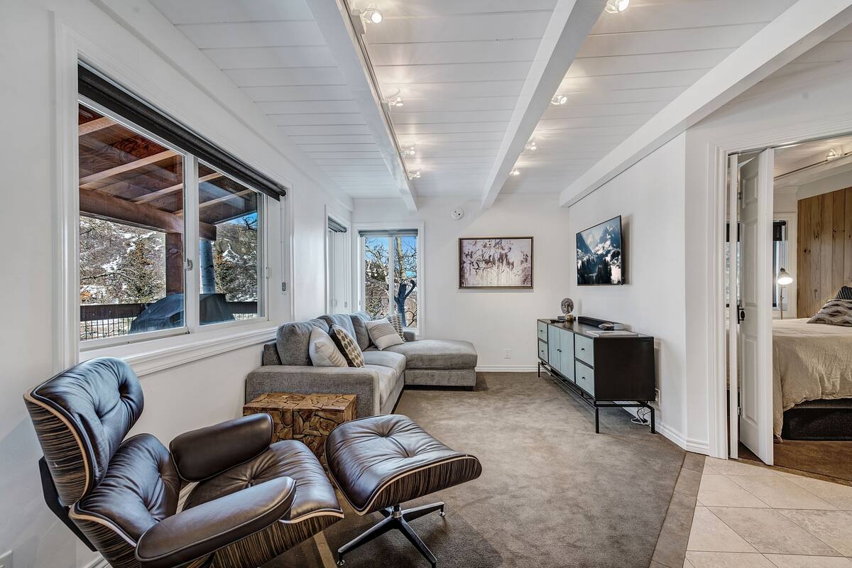 A modern living room with a sectional sofa, leather chairs, a small coffee table, and a TV.