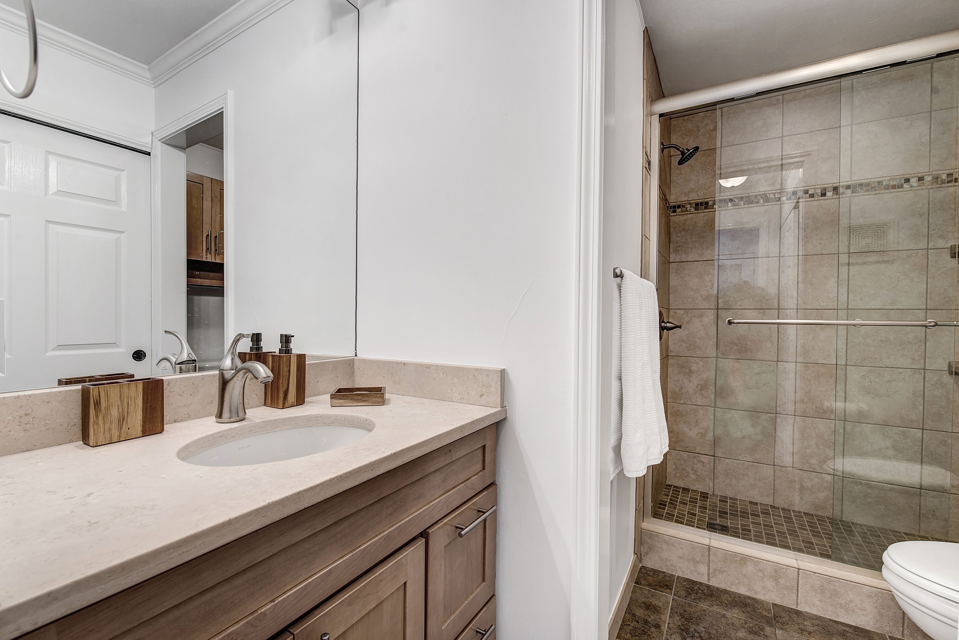 A bathroom with a sink, mirror, and shower.
