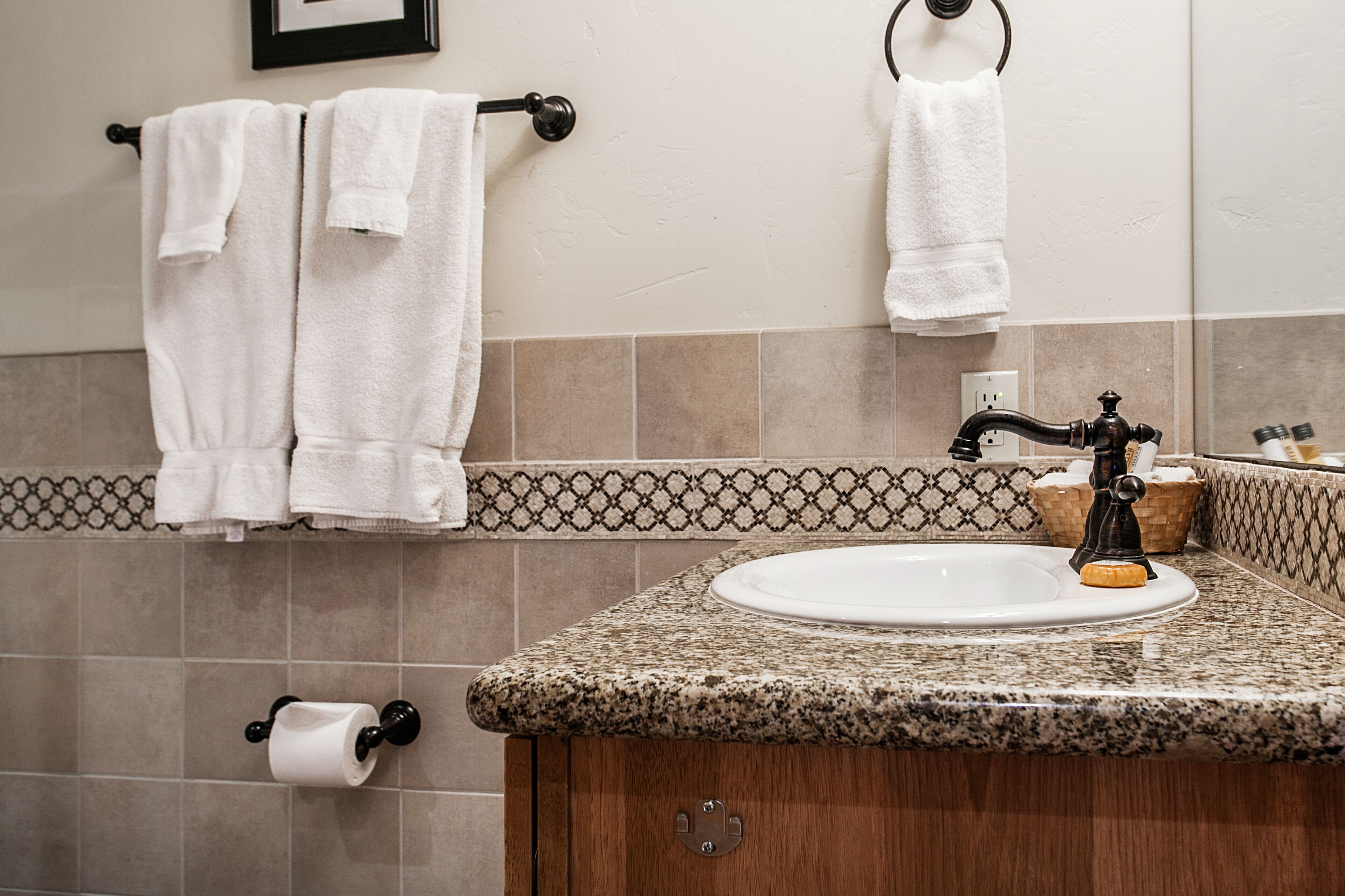 A bathroom with a sink, towel rack, and patterned tiles.