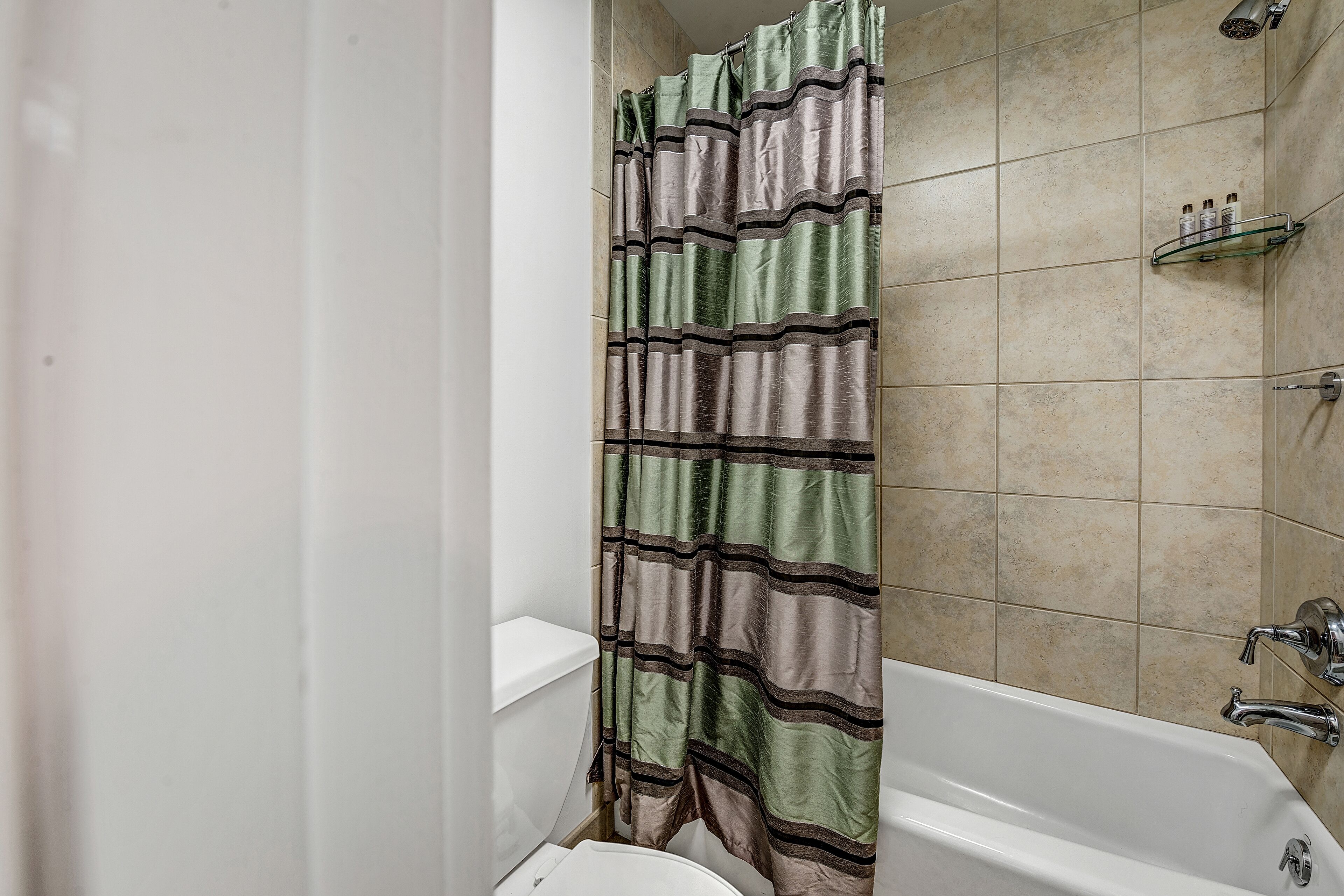 Une salle de bain avec une baignoire, un rideau de douche et une étagère contenant des articles de toilette.