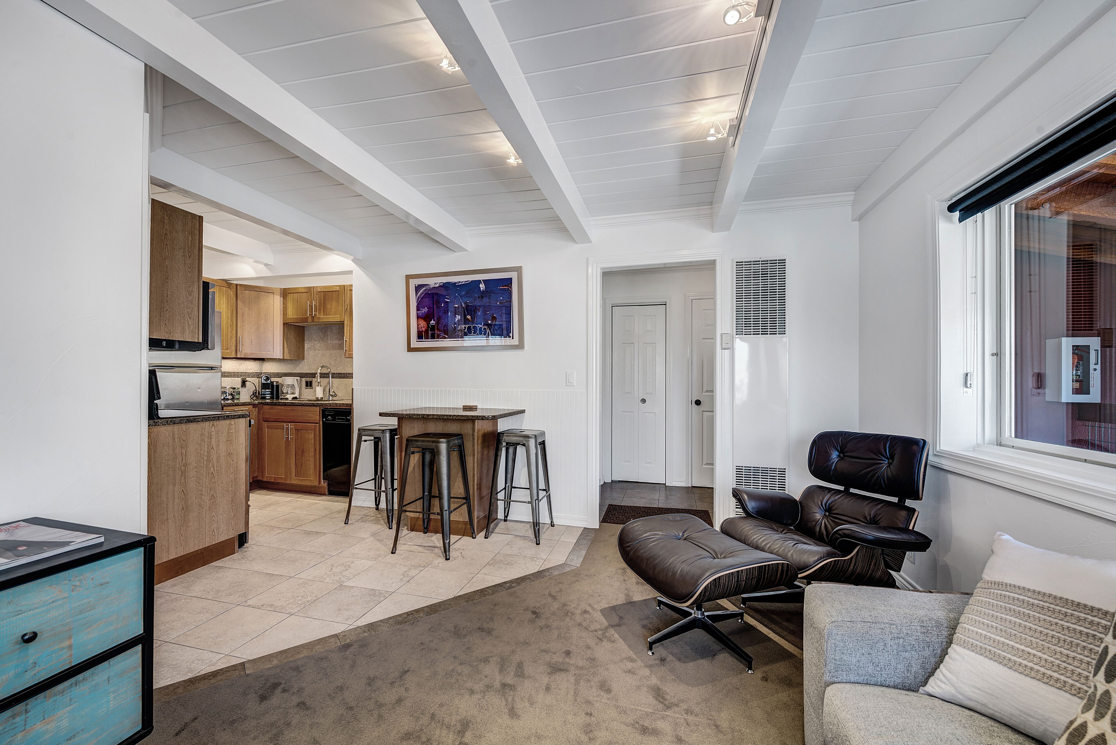 A modern kitchen with wooden cabinets, a bar area, and a dining table with stools.