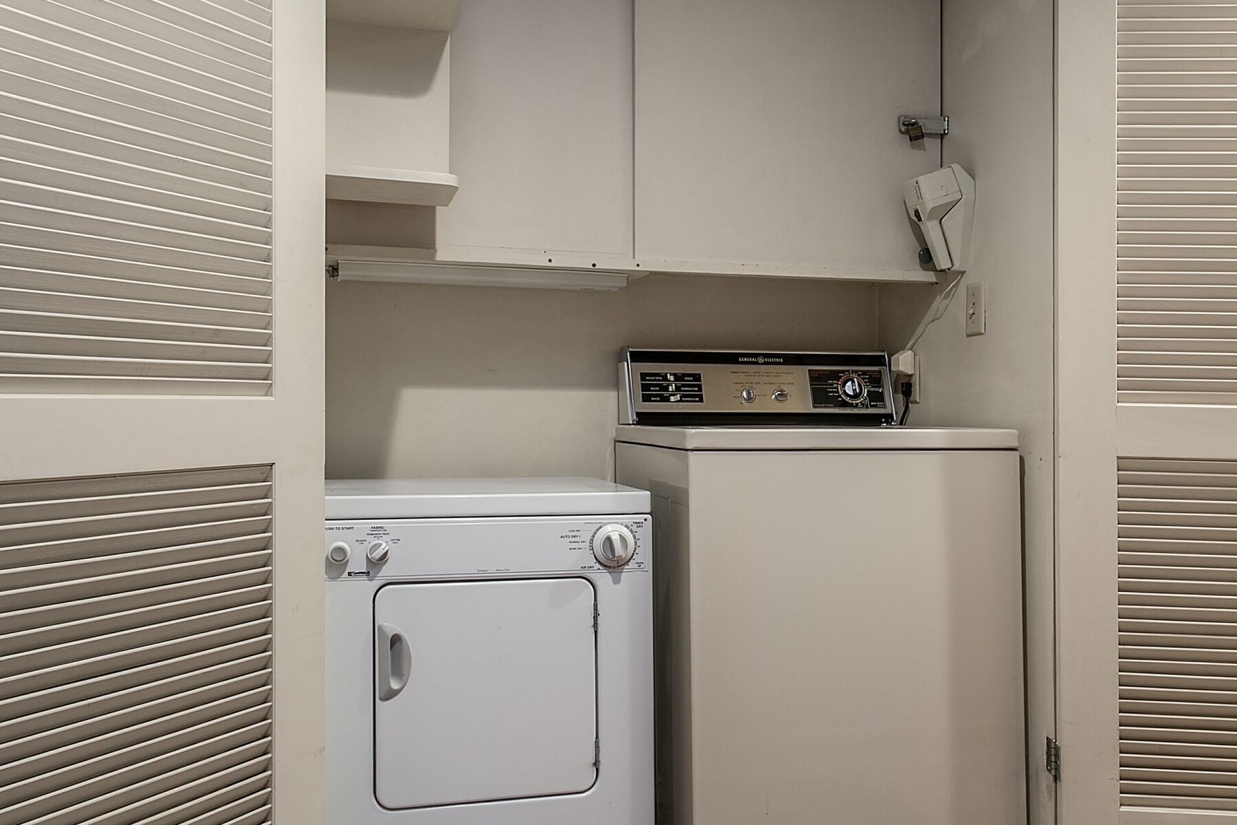 A laundry room with a washing machine, dryer, and a control panel.