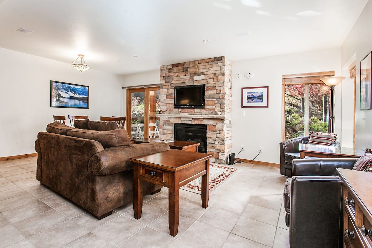 A living room with a stone fireplace, leather sofa, and a television.