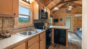Interior de una cabaña de madera con cocina, comedor y sala de estar.