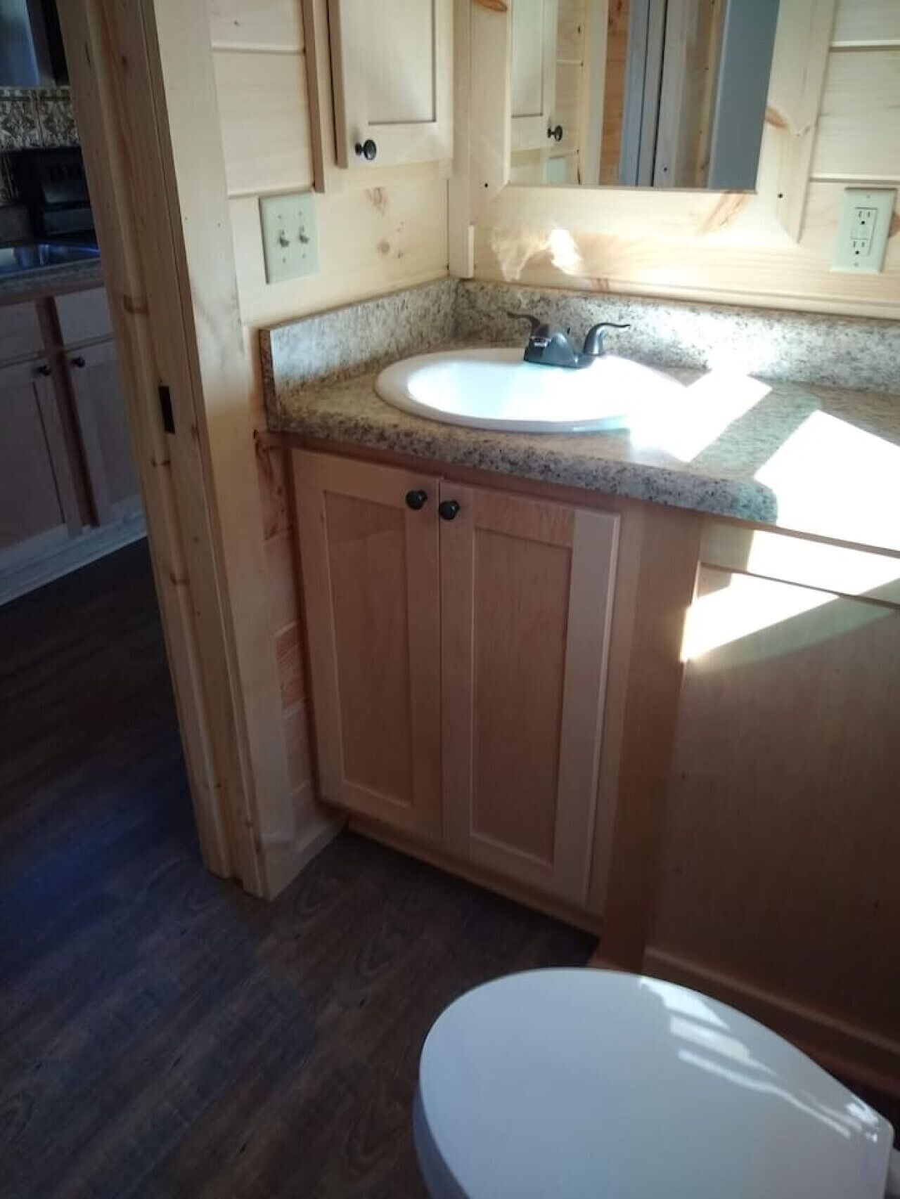 Une salle de bain avec un lavabo blanc, des meubles en bois et des toilettes.