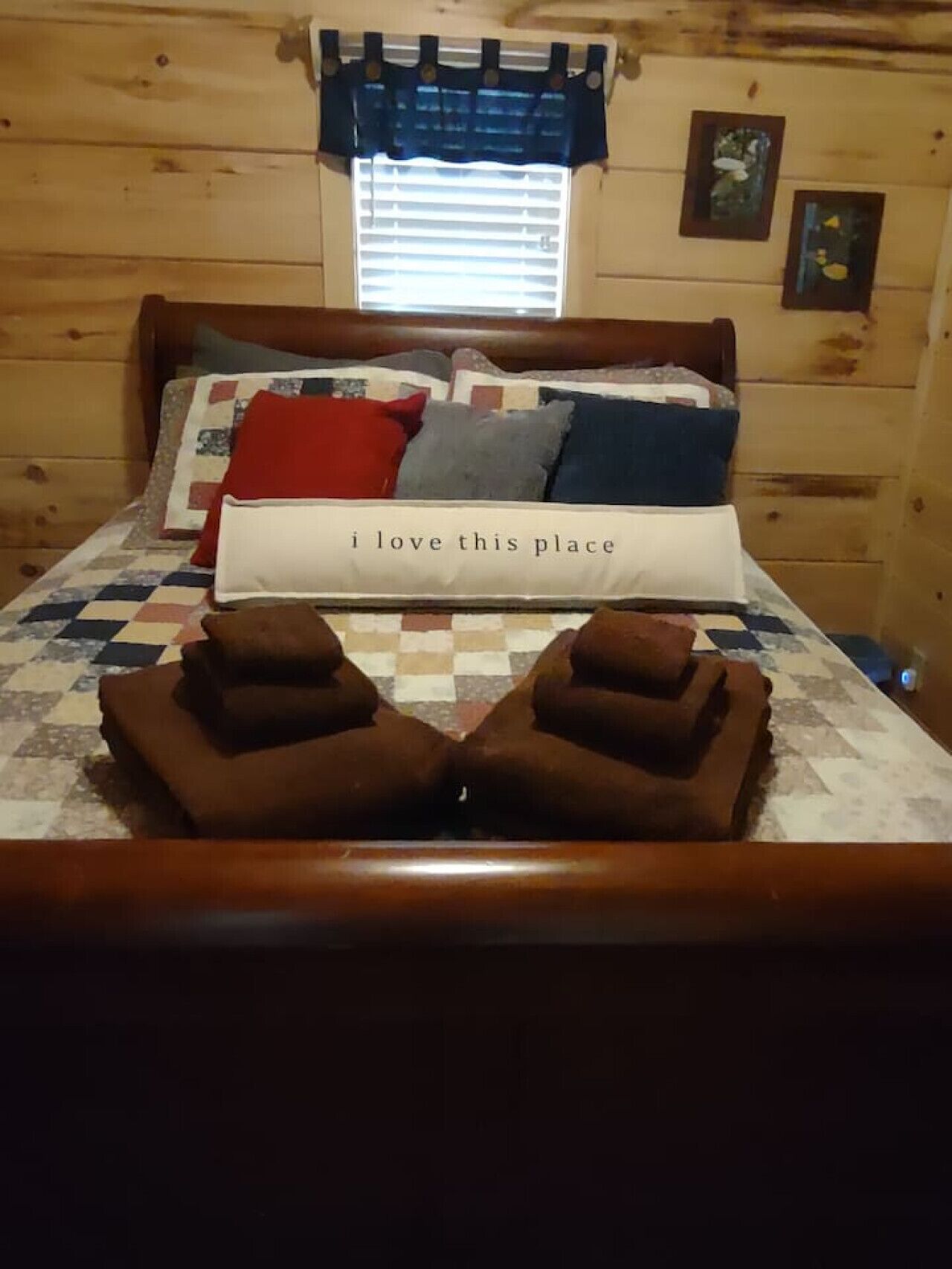 Ein Zimmer in einer Holzhütte mit einem Bett, Kissen, einer Decke und einer Wolldecke.