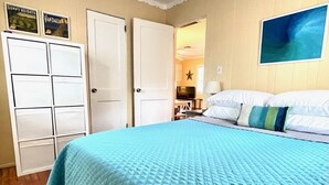 Une chambre avec une couvre-lit matelassée bleue, des murs blancs, une décoration en forme d’étoile et un téléviseur en arrière-plan.