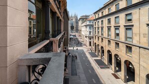 Una vista di una strada fiancheggiata da edifici, tra cui una cattedrale gotica ben visibile in lontananza.