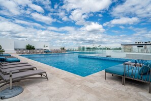 A swimming pool with lounge chairs and a clear sky.