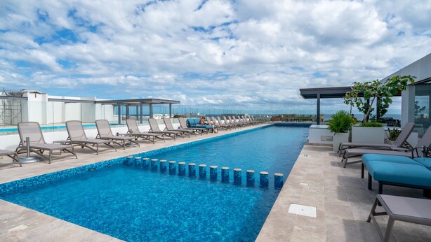 A modern outdoor swimming pool with lounge chairs and a clear view of the sky. - Icaro - With Rooftop At Ipana Condos (Playa del Carmen)