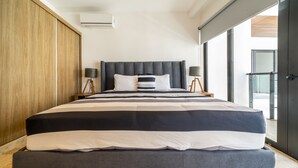A modern bedroom with a large bed, wooden wardrobe, and a view of the outdoors. - Icaro - With Rooftop At Ipana Condos (Playa del Carmen)