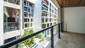 A modern building with multiple balconies, large windows, and a view of the surrounding greenery. - Icaro - With Rooftop At Ipana Condos (Playa del Carmen)