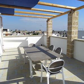 A rooftop terrace with a table and chairs, stone pillars, and a view of the cityscape. - Sea view terrace, 2 bathrooms, 3 bedrooms, living room WiFi Linkem, parking, 2 km mar (Marittima)