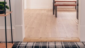A hallway with a wooden floor, a black and white checkered rug, a bench, a table with a bowl, and a hanging light fixture. - Eden Cottage- Quiet City Base (Dundee)
