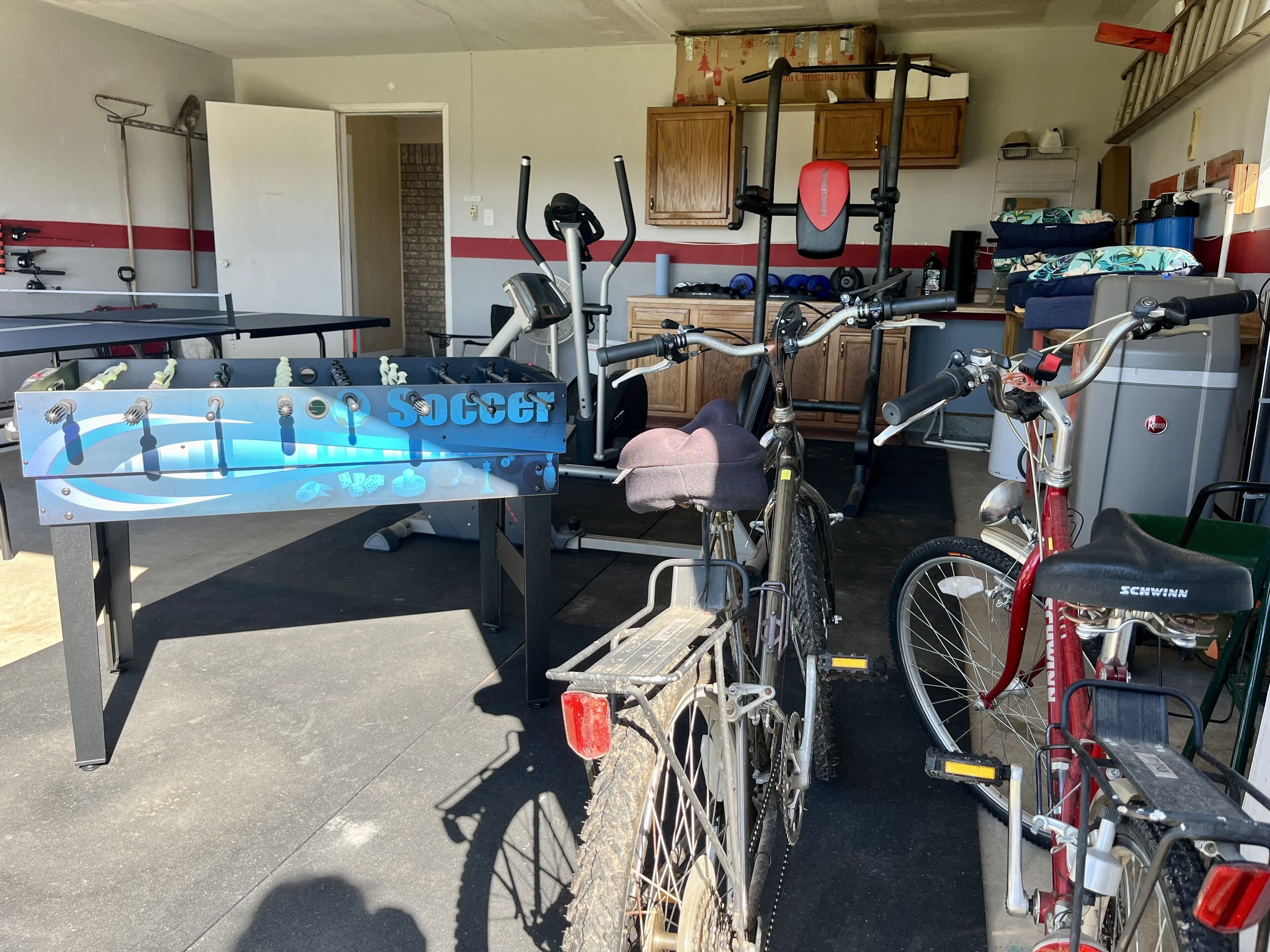 A garage with a bicycle, a foosball table, and various tools.