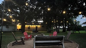A patio area with a bench, two Adirondack chairs, and a fire pit. - Secluded-Prvt fishing-Close to dwntn-firepit-paddleboat-nature trail-KING bed (Brenham)