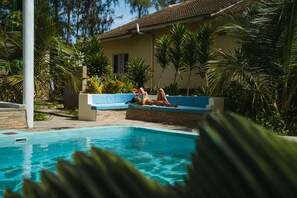 A swimming pool with a person lying on a blue lounge chair. - GK Palm Resort Watamu (Watamu)