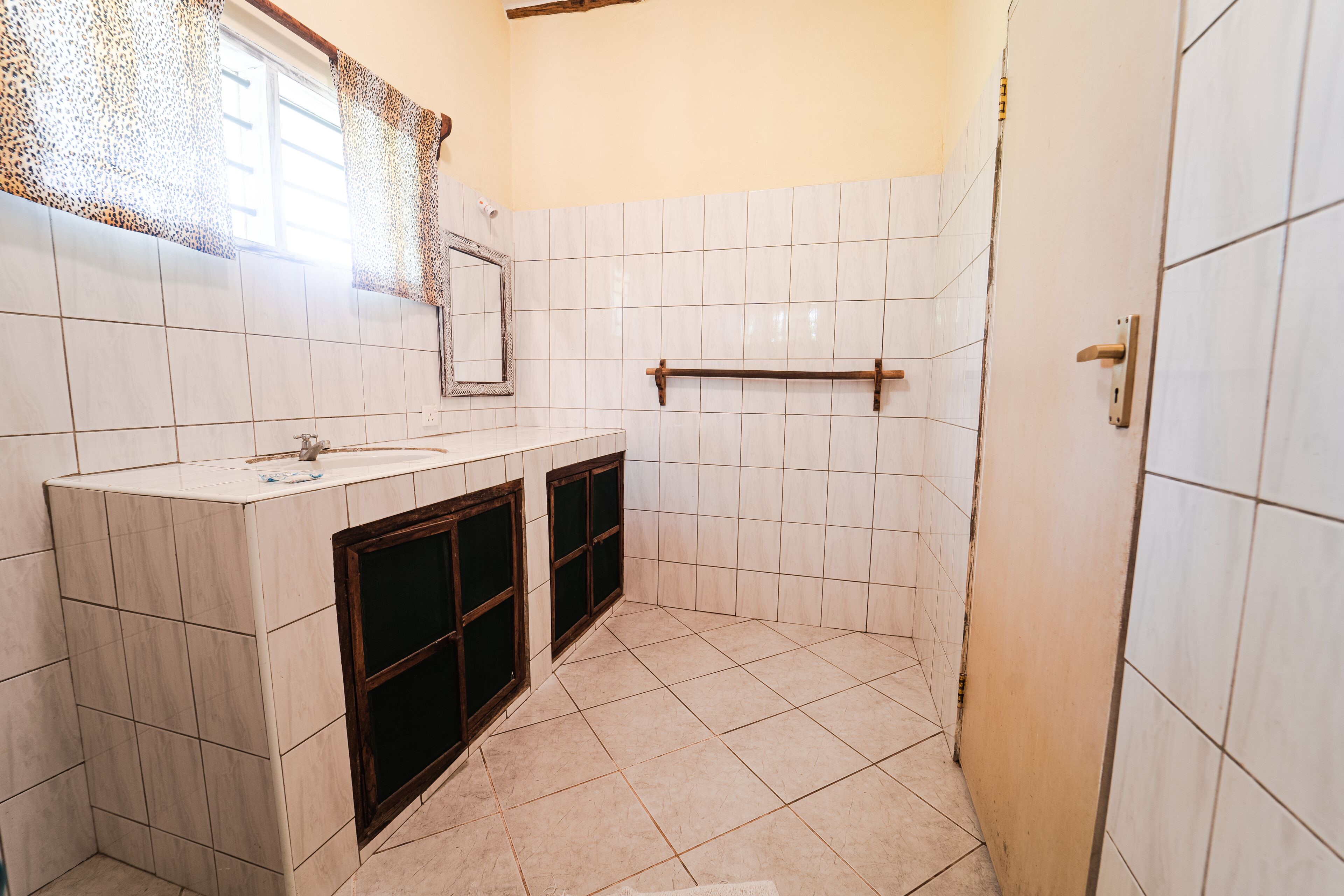 Une salle de bain avec un lavabo, un miroir, un porte-serviettes et des murs carrelés.