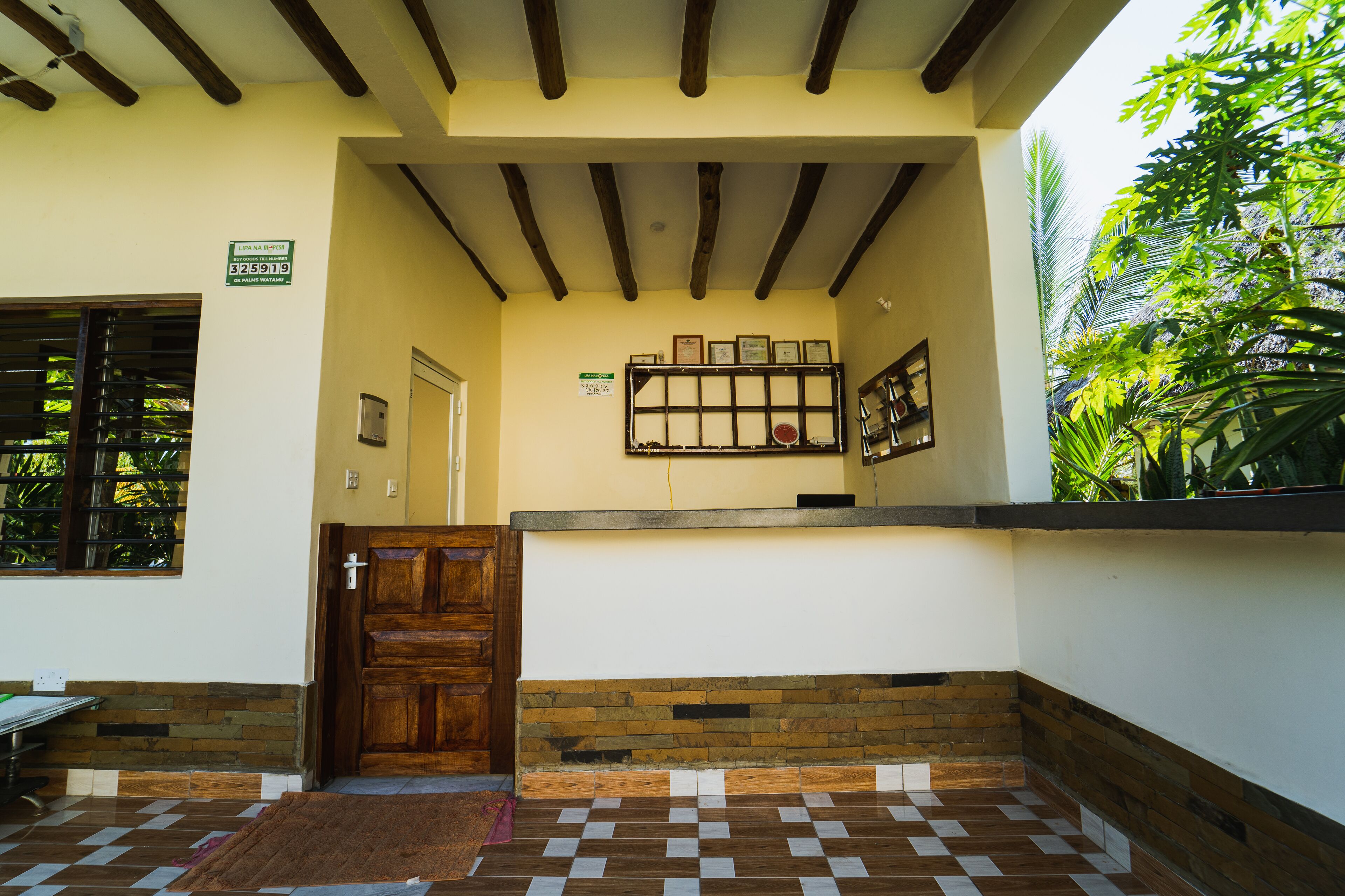 A reception area with a checkered floor, a wooden door, and a wall-mounted display case.