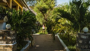 A pathway leading to a building with a reception area, surrounded by lush greenery and a tree. - GK Palm Resort Watamu (Watamu)