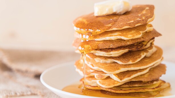 A stack of pancakes with syrup and a pat of butter on top.