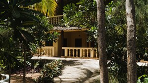 A pathway leading to a thatched-roof building surrounded by palm trees and tropical plants. - GK Palm Resort Watamu (Watamu)