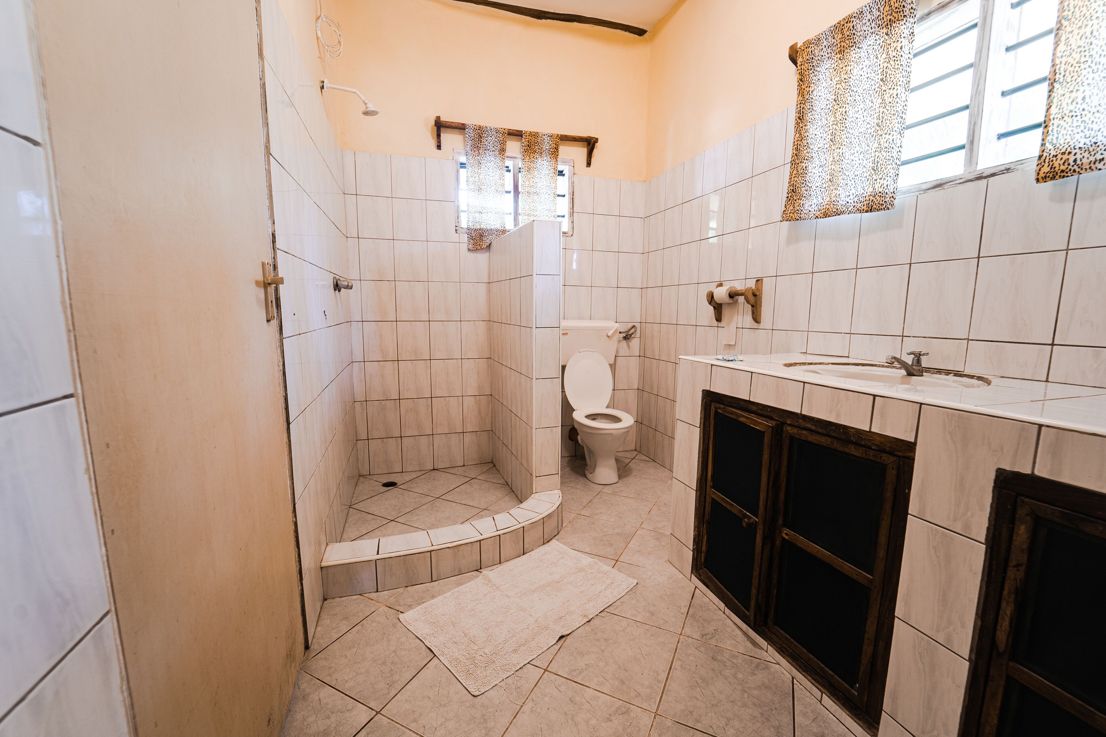 Et badeværelse med bruser, toilet, vask og underskab.
