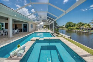 A swimming pool with a covered area, lounge chairs, and a view of a body of water. - Villa Pure Elegance - new building on water with heated pool/spa, for boaters (Cape Coral)