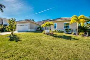 A two-story house with a garage, surrounded by a well-maintained lawn and palm trees. - Villa Pure Elegance - new building on water with heated pool/spa, for boaters (Cape Coral)