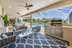 A poolside area with a grill, outdoor seating, and a view of the pool and greenery. - Villa Pure Elegance - new building on water with heated pool/spa, for boaters (Cape Coral)