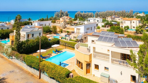 Zona residencial con piscina, paneles solares en los tejados y vista al mar.