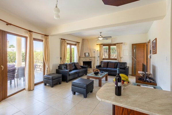 A spacious living room with a fireplace, a dining area with a table and chairs, and a kitchen area with a counter and appliances.