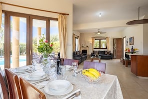 A dining area with a table set for four, a vase with flowers, and a bowl of bananas. - Villa Tsikkos Ena - Three Bedroom Villa, Sleeps 6 (Argaka)