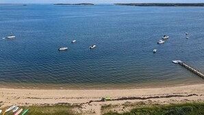 A beach with boats anchored in the water and a pier extending into the sea. - Private Beach - 3 bedroom (Orleans)