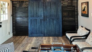 A cozy room with a wooden ceiling, a sliding door, a sofa, and a foosball table. - Private Beach - 3 bedroom (Orleans)